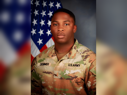 A close-up image of a black army officer student's hands holding a small stack of books. A close-up image of a black army officer student's hands holding a small stack of books.