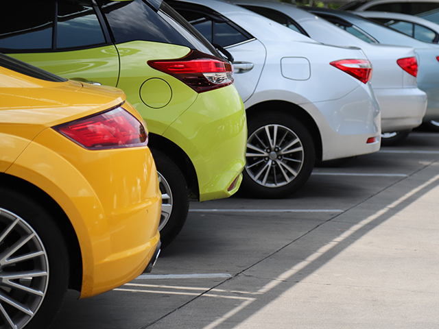 back side of orange color car with other cars parking in parking area