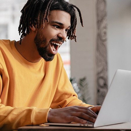 Excied black male student using laptop 