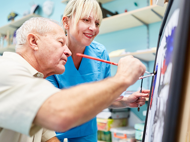 Senior man and therapist are painting together